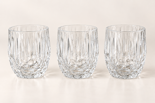 Three clear faceted glass tumblers on a neutral studio background